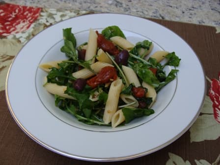 Penne com tomates secos e rúcula